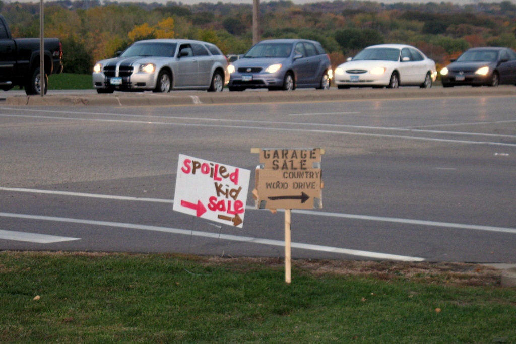 a garage sale sign that reads, spoiled kid sale.