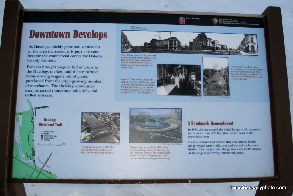 A landmark sign shows a couple of historical photos of the original downtown and the spiral bridge before it was torn down with the new bridge in place.