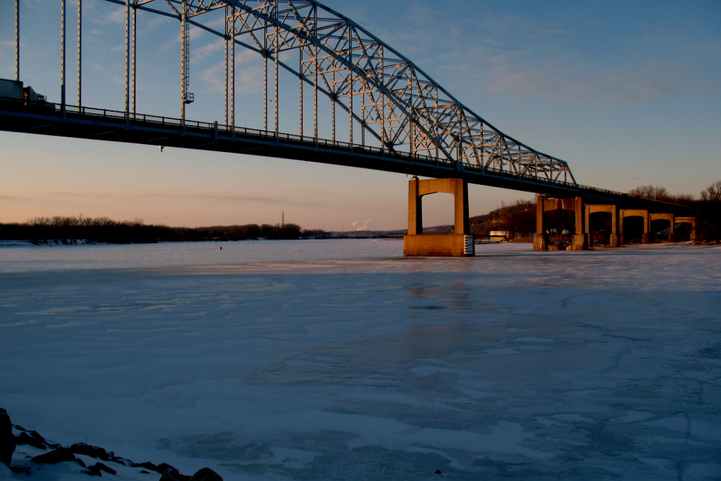 A view of the Hastings River bridge crossing over the frozen Mississippi River during the winter months.