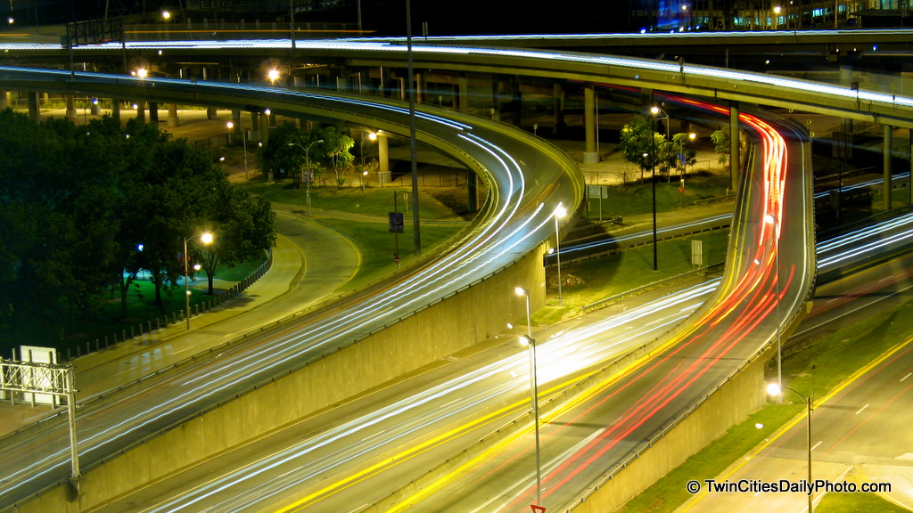 Streaks of light from vehicles on a highway overpass.
